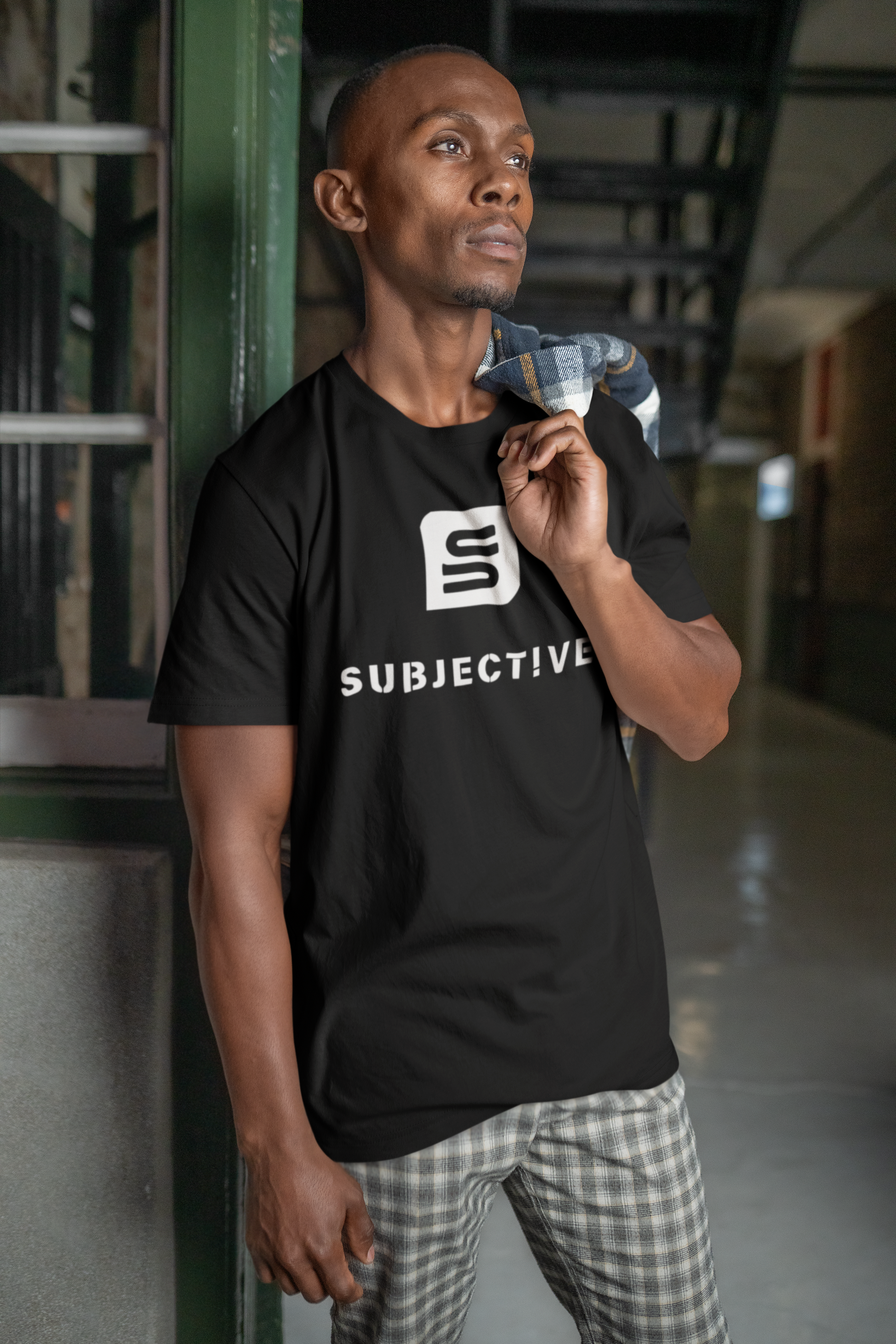 Man wearing a black 'Subjective' t-shirt in an indoor setting